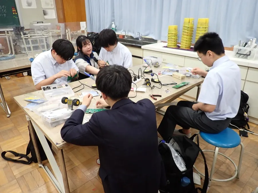 生徒とメンバーがはんだ付けをしている様子